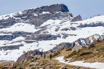 Mountaineers walking on a snowy road with a mountain peak in the background