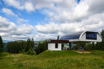 Bukovel ski resort, the upper station. Stationary ski lift chair and cable on mountainside. Shot in summer with green grass and no snow. Carpathian mountains, Ukraine 