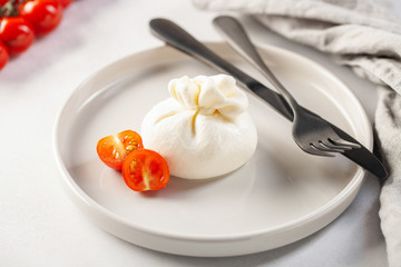 Italian cheese burrata with tomatoes on a plate with a fork