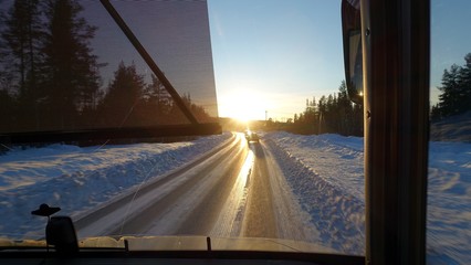 The snowy road seen during sunset from the bus