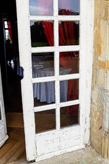 Old white wooden door with glass in an old stone house.