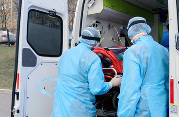 A woman in a hygiene mask and gloves is trying to avoid the coronavirus epidemic. Transportation of the patient in a protective box.