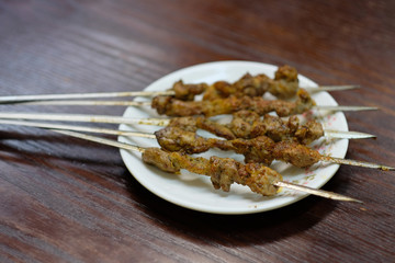 close up several mutton shashlik on plate on wooden table. blur background