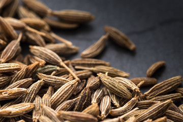 Closeup macro shot of brown caraway seeds on black background
