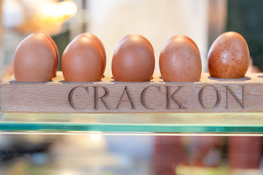 Row of organic chicken eggs in an egg holder on a market stall, with the text 'Crack On'