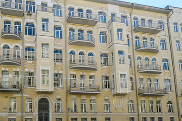 A yellow building with many ornate decors on the front facade. The building has many small windows and balconies. Very detailed construction.
