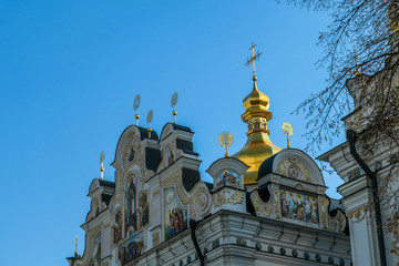 A close-up view on Pechersk Lavra in Kiev, Ukraine, known as the Kiev Monastery of the Caves. It is a historic Orthodox Christian monastery. Green rooftops with golden domes. Walls are painted white.