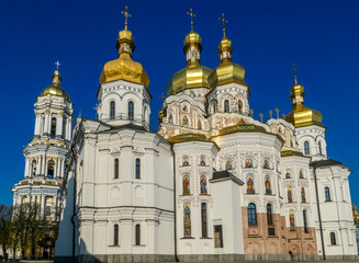 Fototapeta na wymiar A close-up view on Pechersk Lavra in Kiev, Ukraine, known as the Kiev Monastery of the Caves. It is a historic Orthodox Christian monastery. Green rooftops with golden domes. Walls are painted white.