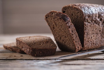 rectangular loaf of rye bread with coriander on a wooden table. slicing bread