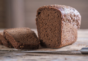 rectangular loaf of rye bread with coriander on a wooden table. slicing bread