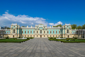 Fototapeta premium Distance view on Mariyinsky Palace, located in Kiev, Ukraine. Palace is painted light blue and sandy colors. Big, open square in front of the palace. Clear and blue sky.