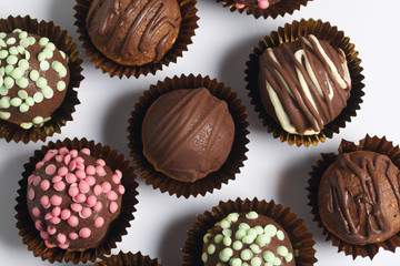 Chocolate Potato Cake. Some decorated with sprinkles, others with chocolate. On white background.