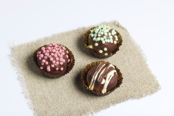 Chocolate Potato Cake. Some decorated with sprinkles, others with chocolate. On white background.