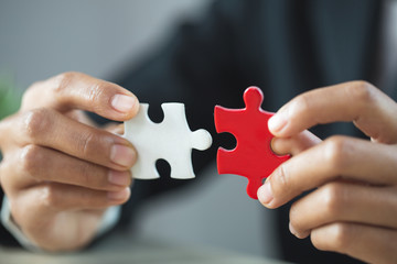 Fototapeta premium Businessman hand connecting jigsaw puzzle, Business solutions, target, success, goals and strategy concepts