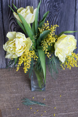 Bouquet of yellow tulips and mimosa. Against the background of brushed boards.