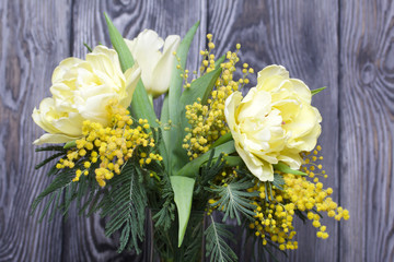 Bouquet of yellow tulips and mimosa. Against the background of brushed boards.