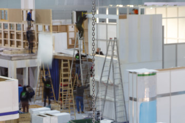 Blurred image of the installation of exhibition constructions. A group of workers on stepladders...