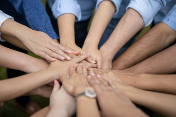 Close up to Asian people hold hand together in the middle of their group, friend with stack of hand showing the love and community of good friends.