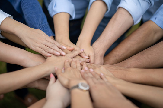 Close up to Asian people hold hand together in the middle of their group, friend with stack of hand showing the love and community of good friends. © Surachetsh