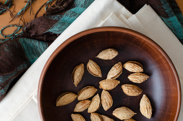 almonds in nutshell on clay dish on linen. Top view