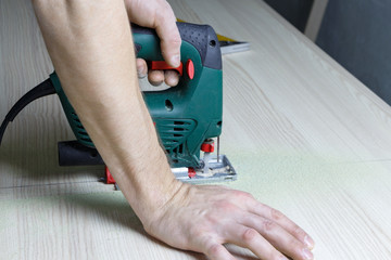 A man is sawing a countertop with a jigsaw.