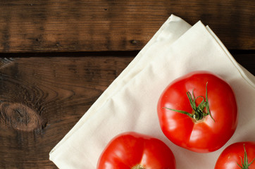 tomatoes on linen on wooden background with copy space. Top view.