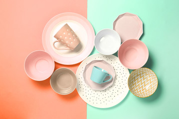 Empty ceramic tableware. Ceramic plates and cups on orange and green background. Set of different modern white and blue plates,bowls and cups.Top view, flat lay.Copy space.