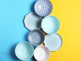 Empty ceramic tableware. Ceramic plates on yellow and blue background. Overview empty food table with tableware. Set of different modern white and blue plates and bowls.Top view, flat lay.Copy space.