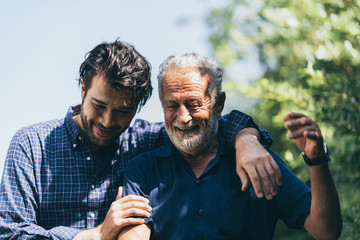 Adult hipster son and old senior father stay for work at home, two generations have a beard talking together and relaxing with smile, happy enjoy living to isolation quarantine at home, father's day - obrazy, fototapety, plakaty