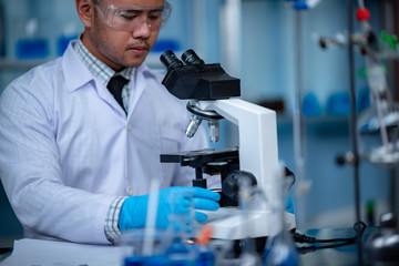 Young scientist looking through a microscope in a laboratory. Young scientist doing some research.