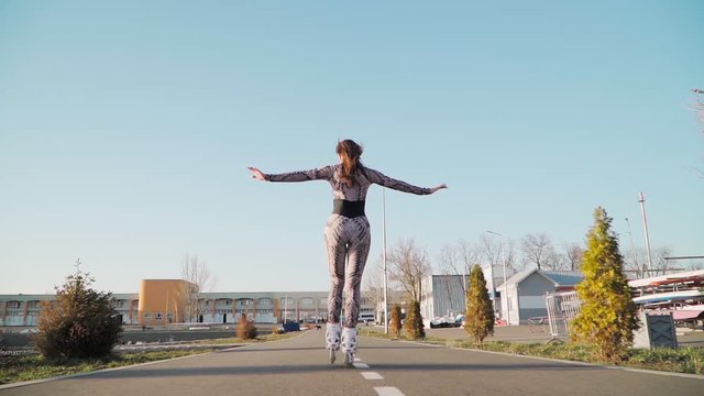 Athletic Slim Rides Girl Roller Skating and happily raises his hands. a young woman enjoys life. Slow motion. Shooting on the Steadicam