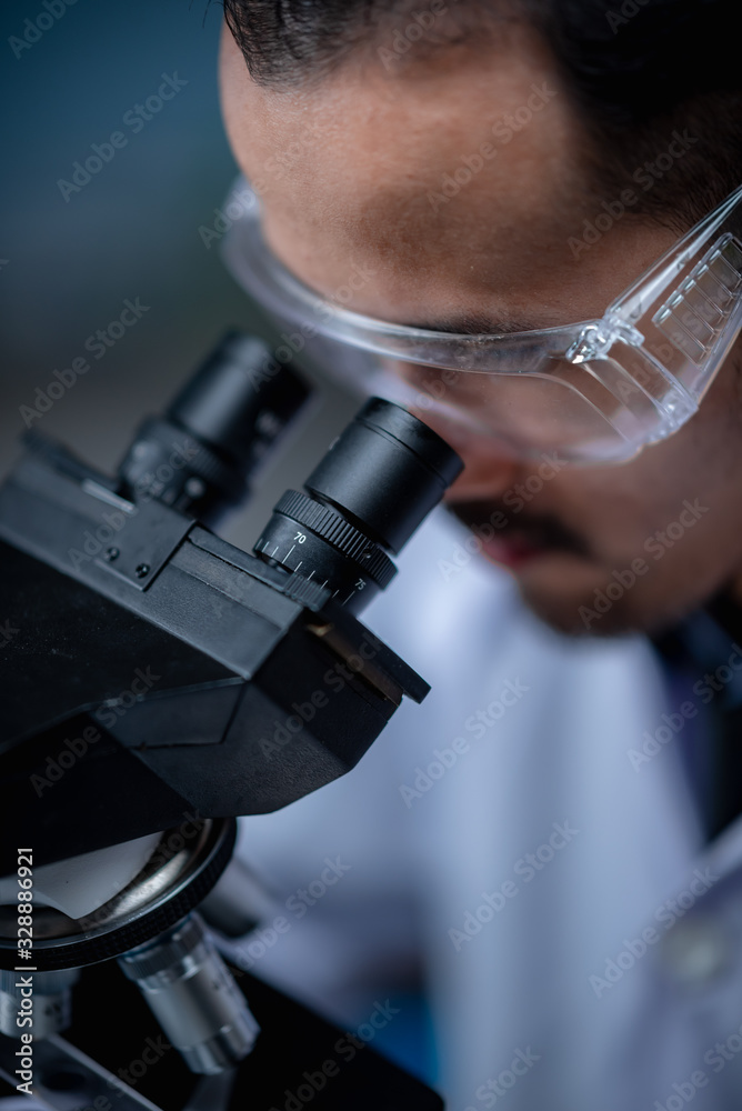 Wall mural young scientist looking through a microscope in a laboratory. young scientist doing some research.