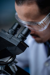 Young scientist looking through a microscope in a laboratory. Young scientist doing some research.