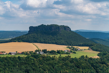 Königstein fortress on the banks of the Elbe river, green landscape with mountains in the background. Dresden, Saxon Switzerland, Germany.