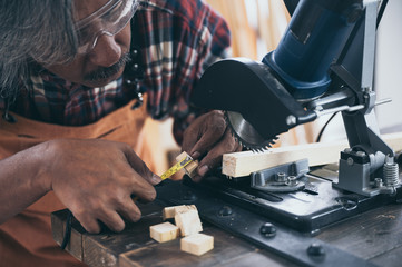 Carpenter working on woodworking machines in carpentry shop, wooden product