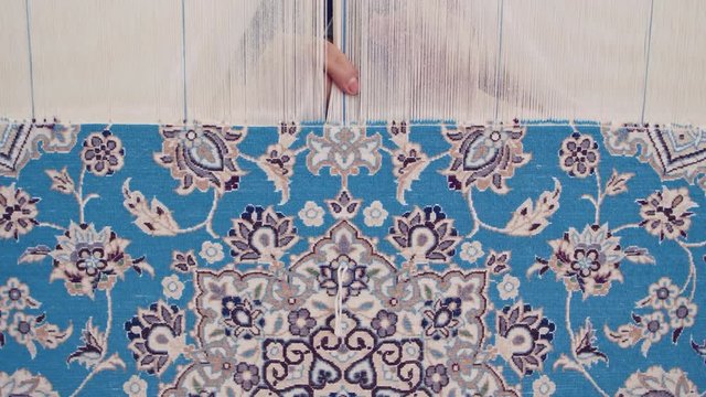 Handheld shot of a old female fingers, working on making a carpet, in Varzaneh, Iran