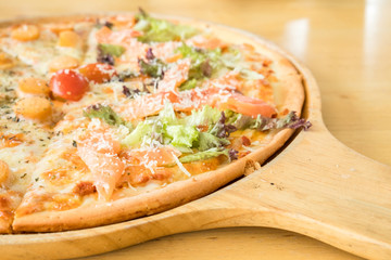 Cutted crust italian sausage and bacon pizza with mozzarella cheese in the wooden pan on the wooden table. Top view of homemade pizza with ingredients. It's junk food and unhealthy food