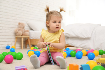 Obraz premium Cute little child with book playing on floor