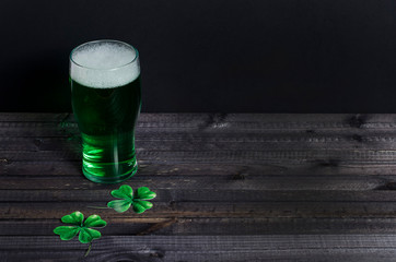 Holiday St. Patrick's Day. Green beer with clover on a dark wooden background with copy space.