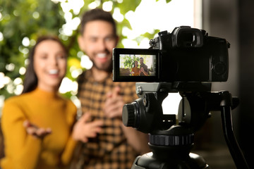 Young bloggers recording video indoors, focus on camera screen