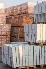 Several pallets with concrete brick stacked on top of each other in depot. Industrial production of bricks. vertical photo