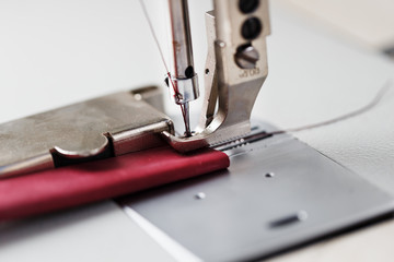 A leather craftsman produces leather goods on a sewing machine in his shop.