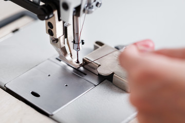 A leather craftsman produces leather goods on a sewing machine in his shop.