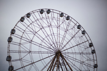 Ferris wheel in the park. City entertainment. Large metal construction. Pleasure vehicle for viewing the cityscape. Attraction for the townspeople. Rest in the park.