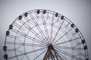 Ferris wheel in the park. City entertainment. Large metal construction. Pleasure vehicle for viewing the cityscape. Attraction for the townspeople. Rest in the park.