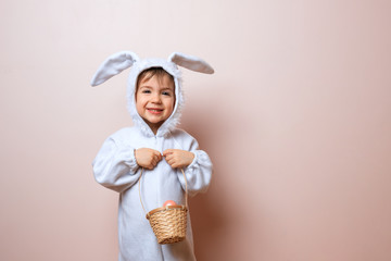 Cute little child boy wearing bunny costume on Easter day. Boy with Easter eggs in the basket.