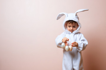Cute little child boy wearing bunny costume on Easter day. Boy with Easter eggs in the basket.