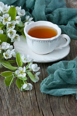 Tea mug and pear flowers on wooden background