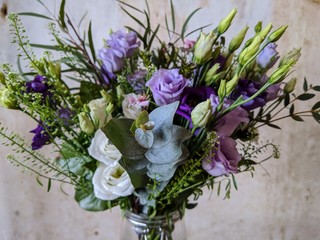 spring bouquet of flowers in glass vase against a textured interior wall