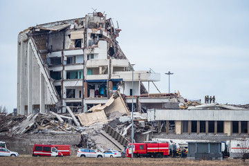 Demolition of a building. Concept - the destruction of dilapidated buildings. Police and fire engines near the ruins. Ruins of a large building on the background of the sky. Dismantling of premises